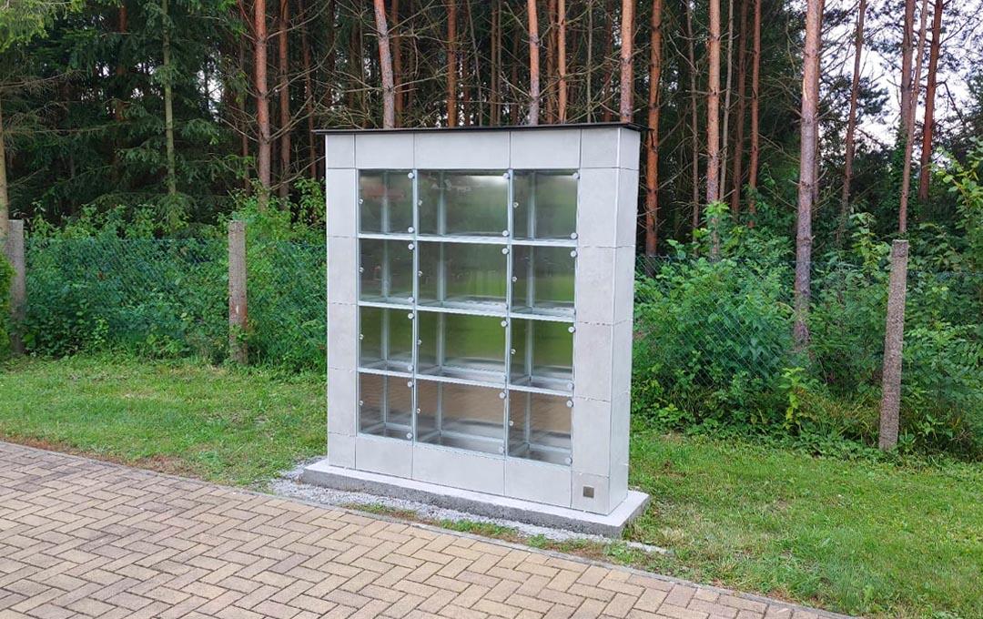 Moderné kolumbáriá s mramorovým obkladom a čiernym rámovaním, obklopené upravenou zeleňou, lavičkami a chodníkmi v upravených priestoroch cintorínov – ukážka riešení od spoločnosti MODU-AL.